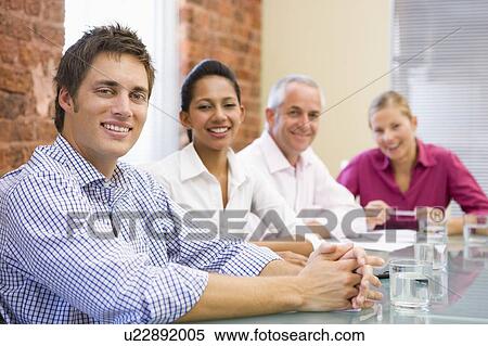 Stock Photography - Four businesspeople in boardroom smiling. Fotosearch