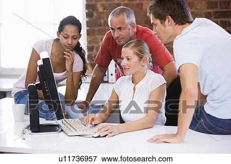 Four businesspeople in office space looking at computer smiling View Large Photo Image Stock Photo - Four businesspeople in office space looking at computer smiling. Fotosearch