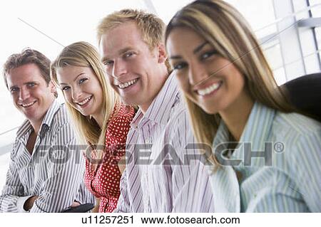 Four businesspeople sitting indoors smiling View Large Photo Image Stock Image - Four businesspeople sitting indoors smiling. Fotosearch