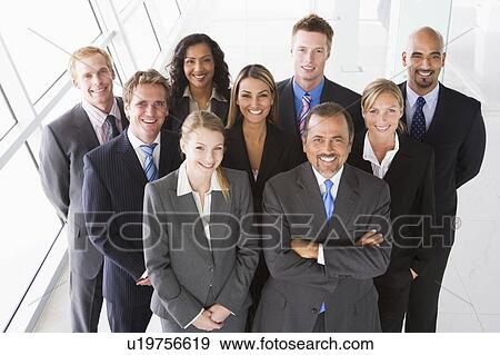 Stock Photo - Group of co-workers standing in office space smiling (high key). Fotosearch