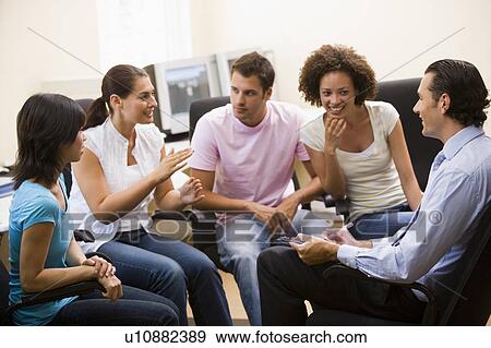 Stock Photo - Man giving lecture to four people in computer room. Fotosearch