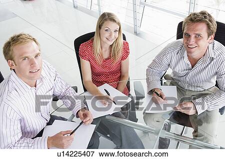 Three businesspeople in a boardroom with paperwork smiling View Large Photo Image Stock Photo - Three businesspeople in a boardroom with paperwork smiling. Fotosearch