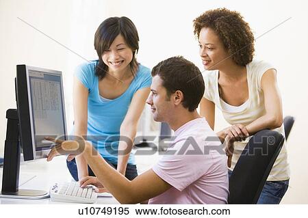 Three people in computer room pointing at monitor and smiling View Large Photo Image Stock Photography - Three people in computer room pointing at monitor and smiling. Fotosearch