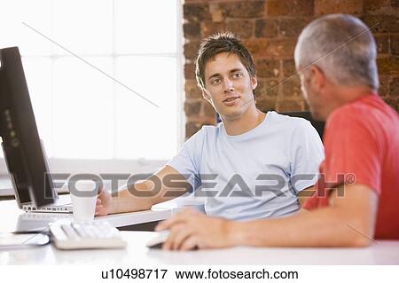 Stock Photo - Two businessmen in office drinking coffee and talking. Fotosearch