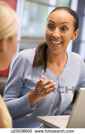 Two businesswomen in boardroom with laptop talking View Large Photo Image Stock Image - Two businesswomen in boardroom with laptop talking. Fotosearch