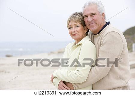 Stock Image - Couple at the beach embracing and smiling. Fotosearch