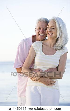 Couple at the beach embracing and smiling View Large Photo Image Stock Photography - Couple at the beach embracing and smiling. Fotosearch