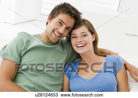 Stock Image - Couple in living room smiling. Fotosearch