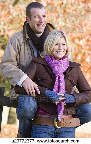 Stock Photo - Couple outdoors in park by fence smiling (selective focus). Fotosearch