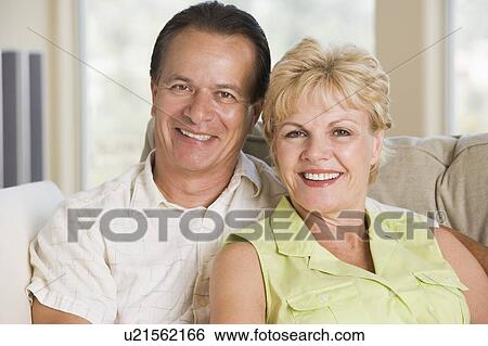 Couple relaxing in living room and smiling View Large Photo Image Stock Photograph - Couple relaxing in living room and smiling. Fotosearch