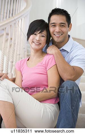 Stock Image - Couple sitting on staircase smiling. Fotosearch