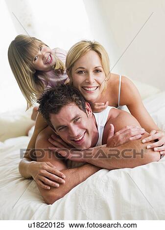 Stock Photography - Family in bed playing and smiling. Fotosearch