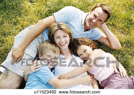 Stock Image - Family lying outdoors smiling. Fotosearch