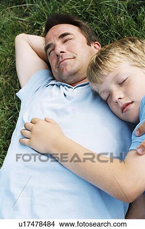 Picture - Father and son lying outdoors sleeping. Fotosearch