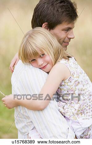 Stock Photo - Father holding daughter outdoors smiling. Fotosearch