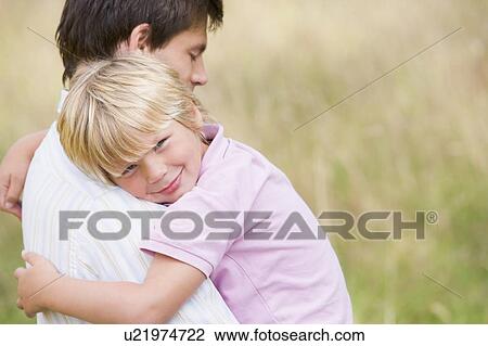 Stock Image - Father holding son outdoors smiling. Fotosearch