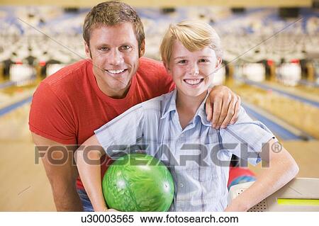 Man and young boy in bowling alley holding ball and smiling View Large Photo Image Stock Photography - Man and young boy in bowling alley holding ball and smiling. Fotosearch
