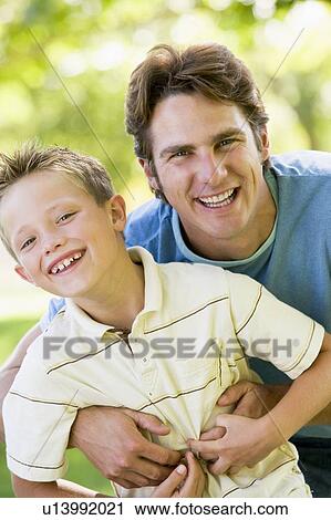 Man and young boy outdoors embracing and smiling View Large Photo Image Stock Image - Man and young boy outdoors embracing and smiling. Fotosearch