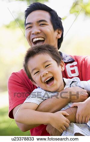 Man and young boy outdoors embracing and smiling View Large Photo Image Stock Image - Man and young boy outdoors embracing and smiling. Fotosearch