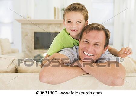 Man and young boy sitting in living room smiling View Large Photo Image Stock Image - Man and young boy sitting in living room smiling. Fotosearch
