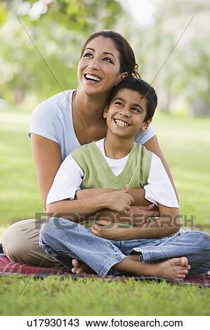 Stock Image - Mother and son outdoors in park bonding and smiling (selective focus). Fotosearch