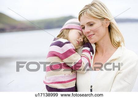 Mother holding sleeping daughter at beach View Large Photo Image Stock Photo - Mother holding sleeping daughter at beach. Fotosearch