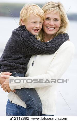 Stock Image - Mother holding son at beach smiling. Fotosearch