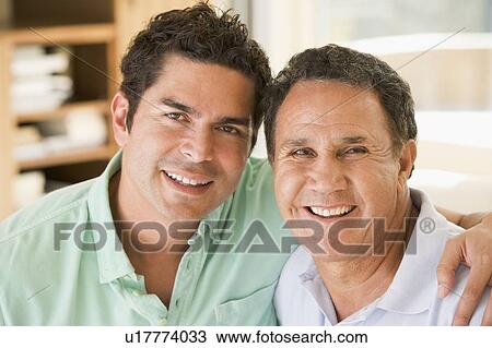 Stock Image - Two men in living room smiling. Fotosearch