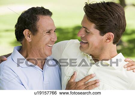 Stock Photograph - Two men standing outdoors bonding and smiling. Fotosearch