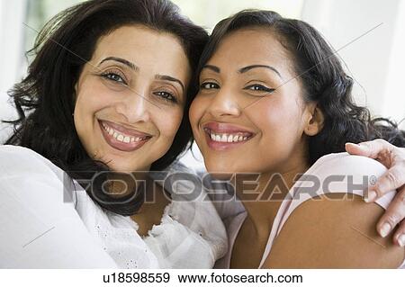 Two women in living room embracing and smiling (high key) View Large Photo Image Stock Photo - Two women in living room embracing and smiling (high key). Fotosearch