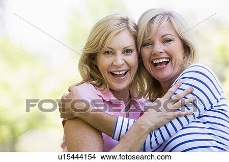 Two women outdoors hugging and smiling View Large Photo Image Picture - Two women outdoors hugging and smiling. Fotosearch