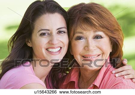 Two women standing outdoors smiling View Large Photo Image Stock Photograph - Two women standing outdoors smiling. Fotosearch