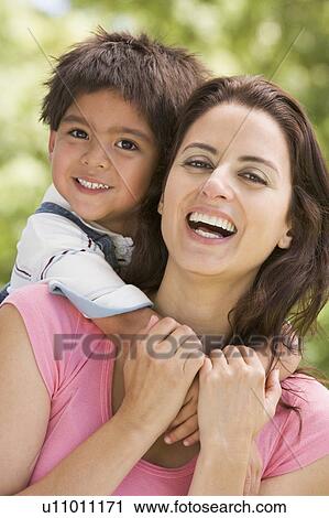 Woman and young boy embracing outdoors smiling View Large Photo Image Stock Image - Woman and young boy embracing outdoors smiling. Fotosearch