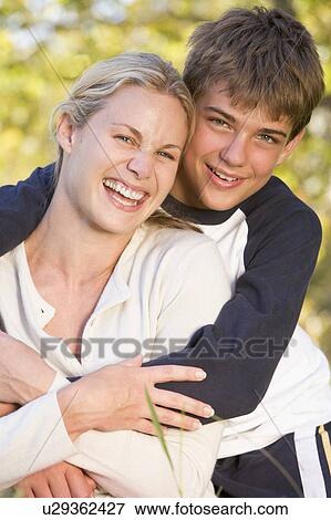 Woman and young boy embracing outdoors and smiling View Large Photo Image Stock Photo - Woman and young boy embracing outdoors and smiling. Fotosearch