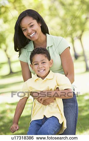 Woman and young boy outdoors embracing and smiling View Large Photo Image Stock Photograph - Woman and young boy outdoors embracing and smiling. Fotosearch