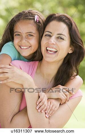 Woman and young girl embracing outdoors smiling View Large Photo Image Stock Photo - Woman and young girl embracing outdoors smiling. Fotosearch