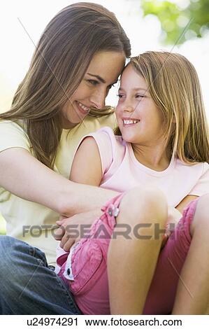 Stock Image - Woman and young girl outdoors embracing and smiling. Fotosearch