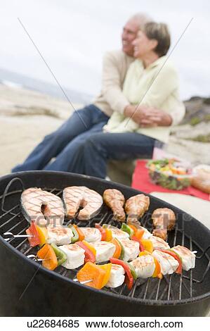 Stock Photography - Couple Cooking On A Barbeque. Fotosearch