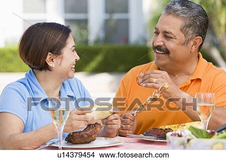 Picture - Couple Enjoying A Barbequed Meal In The Garden. Fotosearch