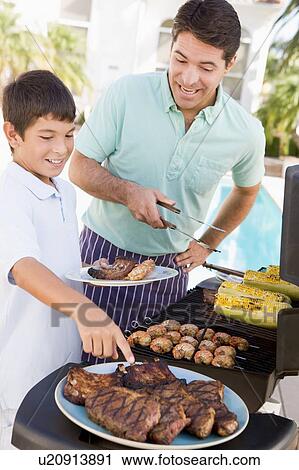 Stock Image - Father And Son Barbequing. Fotosearch