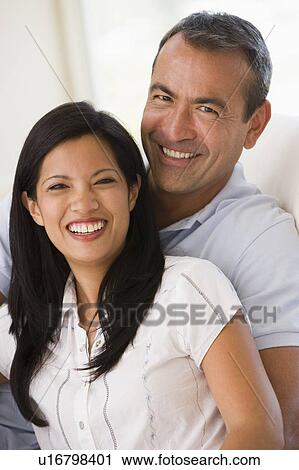 Stock Image - Couple in living room smiling. Fotosearch