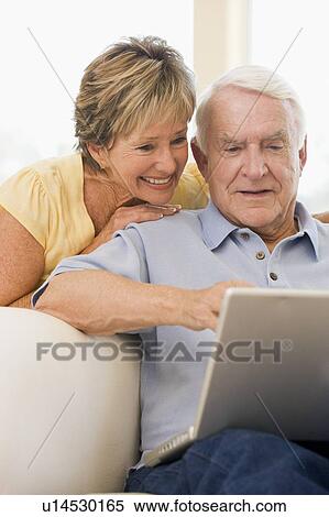 Stock Photography - Couple in living room with laptop smiling. Fotosearch