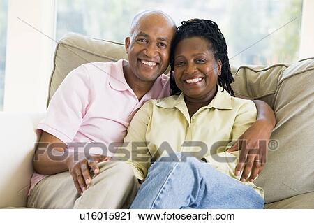 Stock Image - Couple relaxing in living room and smiling. Fotosearch
