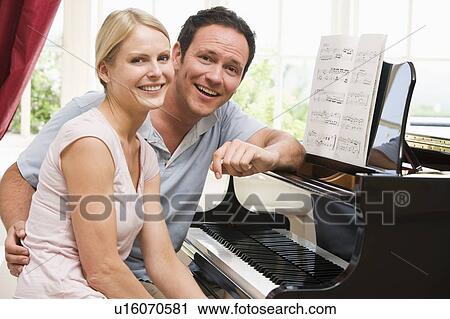 Stock Image - Couple sitting at piano smiling. Fotosearch