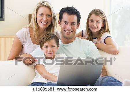 Stock Image - Family in living room with laptop smiling. Fotosearch
