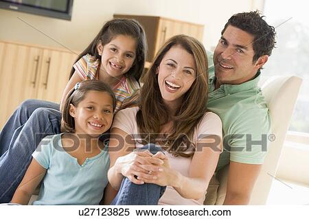 Stock Photography - Family sitting in living room smiling. Fotosearch