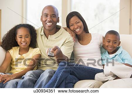 Family sitting in living room with remote control smiling View Large Photo Image Stock Image - Family sitting in living room with remote control smiling. Fotosearch