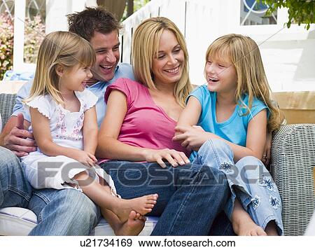 Stock Photo - Family sitting on patio smiling. Fotosearch