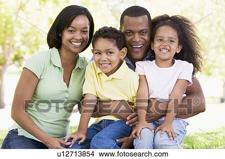 Family sitting outdoors smiling View Large Photo Image Picture - Family sitting outdoors smiling. Fotosearch