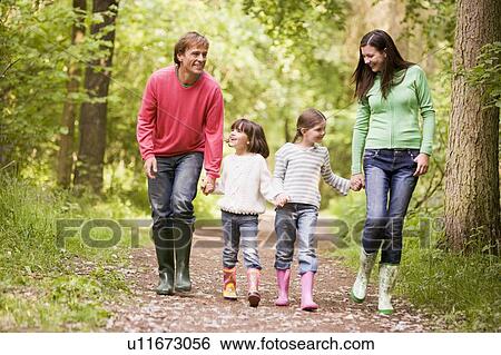 Stock Photograph - Family walking on path holding hands smiling. Fotosearch